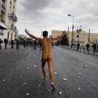 Un manifestante corre desnudo frente al Parlamento en la plaza Sintagma, en Atenas, durante una violenta protesta contra la visita de la canciller alemana, Angela Merkel.