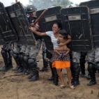 Una mujer indígena sujeta en brazos a su hijo mientras trata de zafarse de los policías estatales que tratan de expulsarla a ello y otros 200 miembros del Movimiento de los Trabajadores Rurales Sin Tierra de un terreno de propiedad privada a l...