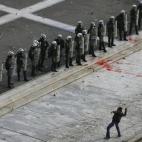 Un manifestante tira una piedra a los policías apostados a las afueras del Parlamento griego durante los violentos choques en Atenas entre la población, azotada por la crisis, y las fuerzas de seguridad que sirven de escudo a los políticos qu...