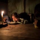 Estiben, Estefany y Javier Aquino cenan a la luz de una vela en el barrio de Nueva Esperanza, Lima, por no tener acceso a electricidad.&nbsp;