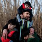 Un hombre llegado desde Afganist&aacute;n abraza a sus hijos tras llegar a la isla de Lesbos, Grecia.&nbsp;