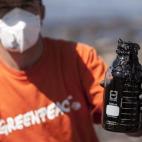 Voluntario de la asociación ecologista Greenpeace muestra el fuel recogido en la playa de Venegueras.