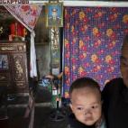Doan Tue, con su nieta, ante una foto suya de cuando era militar. Están en su casa de Truc Ly. Doan Tue también fue soldado y tuvo hijos con discapacidad. 