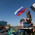 Soldados y civiles sirios ondean banderas de Siria y Rusia contra el ataque de Estados Unidos.