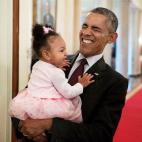 President Barack Obama holds the daughter of former staff member Darienne Page Rakestraw in the Cross Hall of the White House on April 3, 2015.