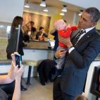 Obama holds a baby while greeting patrons at The Coupe restaurant in Washington, D.C., Jan. 10, 2014.