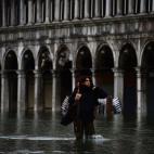 Una mujer pasea por una plaza inundada
