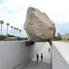 La gente camina por un sendero bajo una roca gigante expuesta en el Museo de Arte del Condado de Los Ángeles (LACMA) el 13 de julio de 2012. El bloque de granito, de 340 toneladas, forma el centro de la escultura Masa en levitación, del artist...