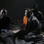 Inmigrantes en situación irregular se sientan en un centro de detención de inmigración en la ciudad de Garabulli, Libia.