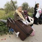 Una niña palestina se sienta en una maleta mientras espera con su familia viaje para cruzar a Egipto, en el cruce de Rafah entre Egipto y el sur de la Franja de Gaza.