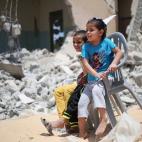 Dos niños palestinos se sientan entre los escombros de los edificios que fueron destruidos en la guerra de 50 días entre Israel y militantes de Hamás durante el verano de 2014 en el pueblo de Khuzaa, al sur de la Franja de Gaza.