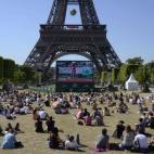 Las personas se sientan en el césped de Champ de Mars para ver el partido de la semifinal femenina de Roland Garros 2015 en una pantalla gigante al pie de la Torre Eiffel en París, Francia.