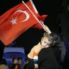 Una votante partidaria del AKP, el partido islamista en el poder, sostiene a una niña en brazos mientras ondea una bandera en la sede de la formación.