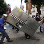 Un hombre transporta un refrigerador recién comprado frente a una tienda de electrodomésticos de Caracas, Venezuela.