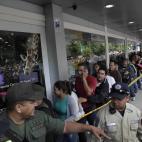 Un miembro de la Guardia Nacional organiza una fila en las afueras de un mercado en Caracas.