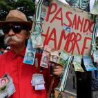 An opposition demonstrator holds a placard with the image of human skeleton, Bolivar bills attached to it and a legend reading 'going hunger', during a protest against President Nicolas Maduro's government, called by opposition leader and self-p...