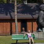 Una mujer descansa junto a una estatua de Lenin.