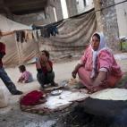Una mujer desplazada prepara pan para sus niños en una fábrica abandonada en la ciudad de Alepo, Siria. 
