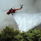 Un helicóptero sobrevuela la zona para sofocar un incendio en el suburbio de Karea en Atenas (Grecia).