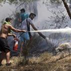 Varios voluntarios intentan extinguir las llamas en el suburbio de Karea en Atenas (Grecia).