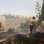 Un hombre intenta extinguir las llamas en el suburbio de Karea en Atenas (Grecia).