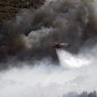 Un helicópetro intenta sofocar un incendio en el suburbio de Karea en Atenas (Grecia).