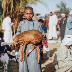 Un niño lleva en brazos una cabra en el mercado de los sábados en Sayala, conocido como mercado de Kalabsha en Kom Ombo. Desde que tienen medios para almacenar los alimentos, la gente suele hacer la compra semanalmente. 5. Hassan vendiendo alf...