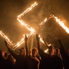 Un grupo de adeptos del Movimiento Nacional Socialista hace el saludo nazi durante la quema de una esv&aacute;stica, en Georgia, Estados Unidos.