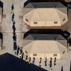 Un grupo de inmigrantes reci&eacute;n detenidos en la frontera de M&eacute;xico son conducidos entre las tiendas de campa&ntilde;a del centro de detenci&oacute;n, en Texas.