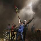 Un grupo de manifestantes palestinos grita durante los enfrentamientos contra las tropas israel&iacute;es en una protesta en la que exigen el derecho al retorno de los refugiados, en la frontera entre Israel y Gaza.