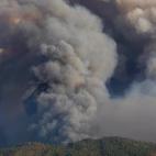 Un avi&oacute;n vuela a trav&eacute;s de una columna de humo producto de un incendio forestal en Vila do Rei, Castelo Branco.