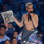 Katy Perry tras quitarse el traje de astronauta con un periódico en el que se lee '¡El mundo está en llamas!'
