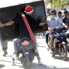 Un hombre transporta en moto una televisi&oacute;n en Palu.