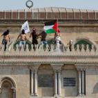 Varios fieles palestinos ondean unas banderas encima de la mezquita de Al Aqsa.