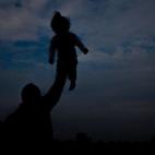 Sujetándola con una mano por encima de su cabeza, un padre juega con su hija en el centro para refugiados y migrantes de Sid (Serbia). El país es un territorio de tránsito en el éxodo de los refugiados hacia el norte de Europa. 