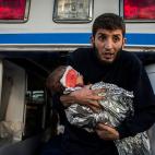 Un hombre con un bebé herido por una bala en la cabeza en Mosul, saliendo de la ambulancia en el puesto de control de Bartella. La ofensiva contra el Estado Islámico ha provocado miles de heridos y muertos entre la población civil. Bartell...