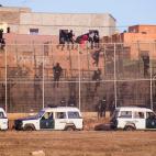 Un grupo de malienses queda encaramado a la valla de Melilla con la esperanza de no ser deportados a Marruecos. Minutos m&aacute;s tarde fueron devueltos en caliente al pa&iacute;s vecino por parte de la guardia civil. Agosto de 2014.