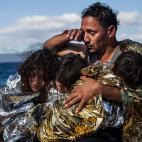 Un padre arropa a sus tres hijos con una manta térmica ofrecida por personas voluntarias, en una playa de la isla griega de Lesbos después de cruzar el Egeo desde Turquía, en una precaria embarcación. Lesbos, Grecia. Octubre de 2015.