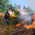 Un residente de la zona afectada lanza un cubo de agua al fuego cerca de Cernache do Bonjardin.