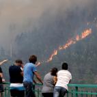 Varios civiles contemplan las llamas el domingo desde un mirador.