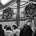 Un fan de Los Beatles escala la puerta del Palacio de Buckingham mientras la reina Isabel II nombra al grupo Miembro de la Orden del Imperio Brit&aacute;nico en octubre de 1965.