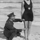 Un polic&iacute;a comprueba el largo del ba&ntilde;ador de una mujer para ver si cumple con el reglamento, en Florida, 1935.