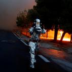 Un bombero se protege con un traje resistente a las llamas mientras el bosque arde.