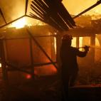 Un bombero lucha contra el fuego que ha carbonizado una casa de Rafina.