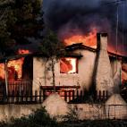 Una casa arde en Kineta, fruto de un incendio forestal que ha invadido el pueblo.