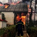 Un bombero contempla, sin poder hacer nada, c&oacute;mo arde una casa en Kineta.