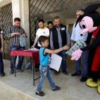 Un hombre vestido de Mickey Mouse reparte certificados y regalos a los estudiantes en el colegio "Siria, La Esperanza" en la ciudad de Maarat an-Numan, Siria.