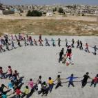 Los estudiantes forman un círculo mientras juegan durante la celebración de fin de curso en el colegio "Siria, La Esperanza".