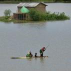 Una mujer y sus hijos cruzan por una de las zonas afectadas por las inundaciones en Morigaon, estado de Assam, India.