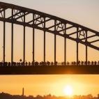 Varias personas cruzan un puente sobre el río Waal durante el primer día de la 100 edición de la Cuádruple Marcha Internacional de Nimega, Holanda. Este evento anual, que se celebra desde 1909, reúne a numerosos participantes que realizan m...